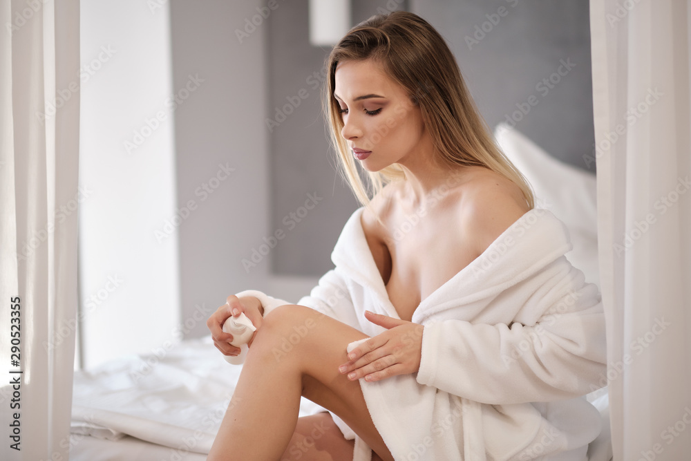Portrait of pretty young woman applying body cream on skin Portrait of pretty young woman applying body cream on skin