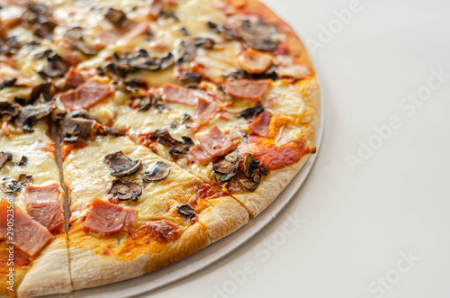 Freshly baked large pizza with ham, mushrooms and mozzarella on a traditional dough