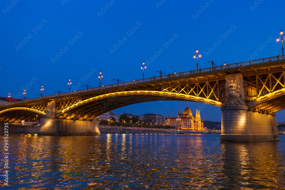 The Margaret Bridge with Parliament Building on background in Budapest, Hungary, illuminated above the Danube river at night.