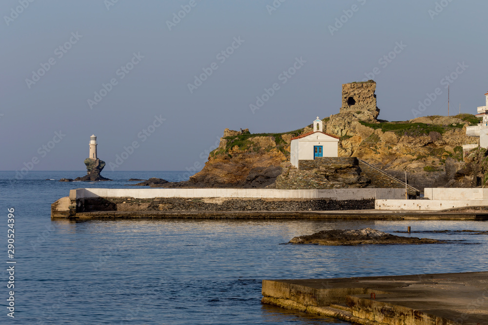 View of the town lighthouse, fortress, church and the sea (Greece, island Andros, Cyclades)