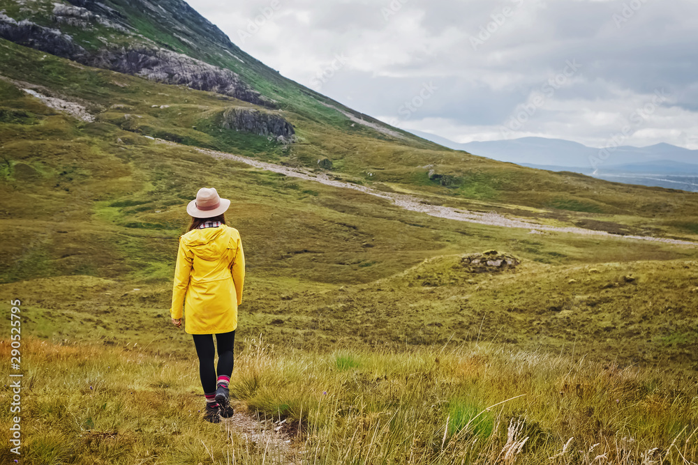 Young woman traveller in hat and raincoat hiking in the rainy mountains Young woman traveller in hat and raincoat hiking in the rainy mountains