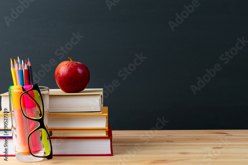 World teacher day - apple and books with pencils and eyeglasses on table in classroom.