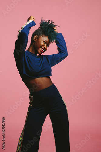 Cool young woman dancing in a blue sweatshirt  with arms up