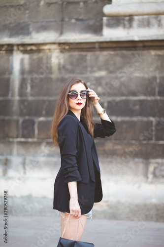 Elegant girl in sunglasses walks around the city