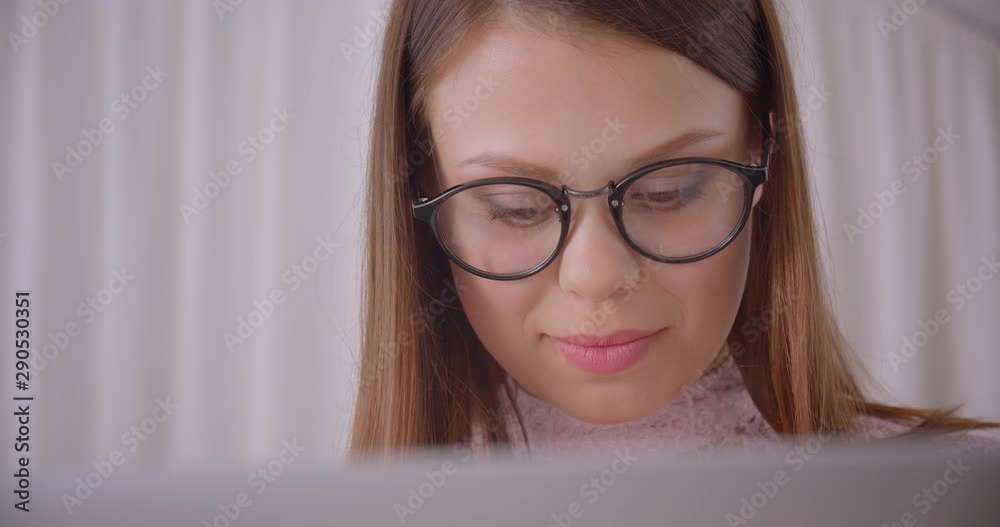 Closeup portrait of young attractive caucasian businesswoman in glasses typing on laptop indoors in apartment Closeup portrait of young attractive caucasian businesswoman in glasses typing on laptop indoors in apartment