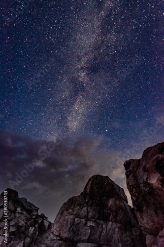 View of the milky way galaxy in the blue sky above the clouds and rocks