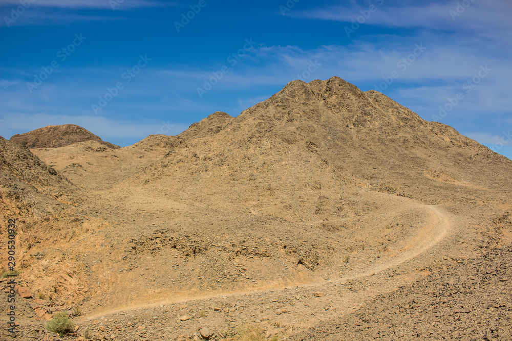 desert sand stone wilderness dunes dry scenery landscape wasteland environment with ground trail bare mountain peak and vivid blue sky desert sand stone wilderness dunes dry scenery landscape wasteland environment with ground trail bare mountain peak and vivid blue sky