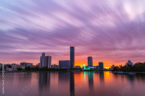 Beautiful purple and orange cloudy sunset at the city pond. Long Exposure cityscape of Yekaterinburg  Russia with skyscrappers reflecting in water