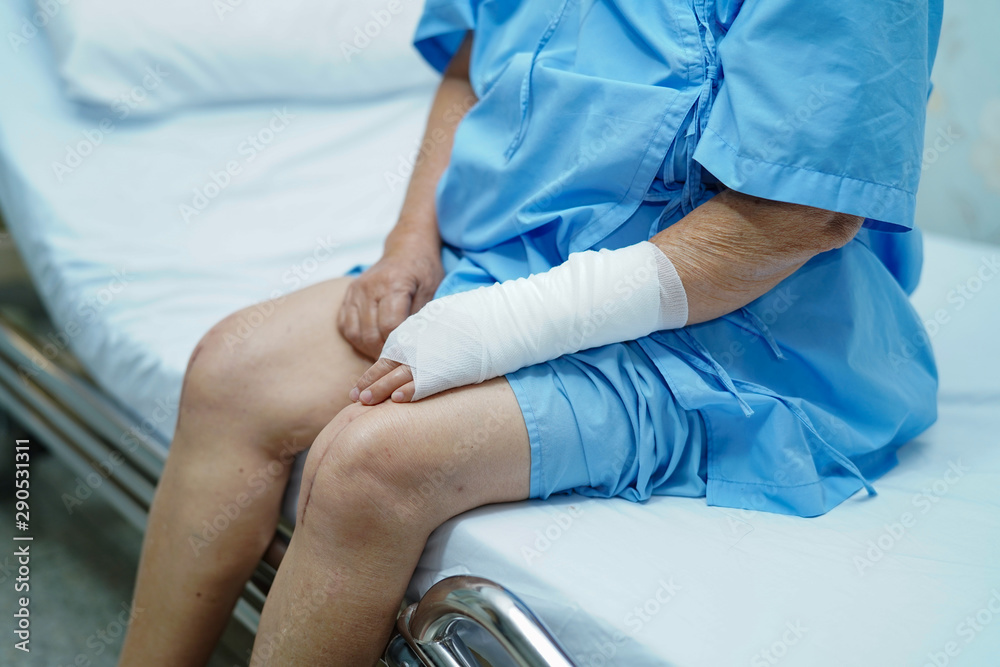 Asian senior or elderly old lady woman patient accident at arm with bandage on bed in nursing hospital ward : healthy strong medical concept.. Asian senior or elderly old lady woman patient accident at arm with bandage on bed in nursing hospital ward : healthy strong medical concept..