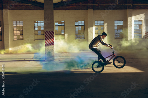 BMX rider in an empty warehouse using smoke grenade photo