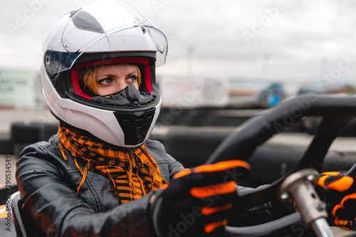Portrait of a pretty girl wearing a white helmet close up, detail of Go-kart. karting track racing, copy space. serious look, determination, active lifestyle, extreme sport © Sergey