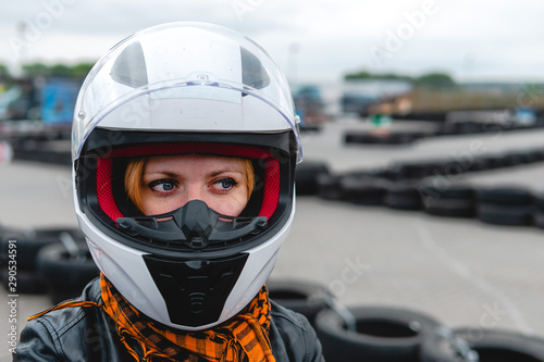 Portrait of a pretty girl wearing a white helmet close up, detail of Go-kart. karting track racing, copy space. serious look, determination, active lifestyle, extreme sport