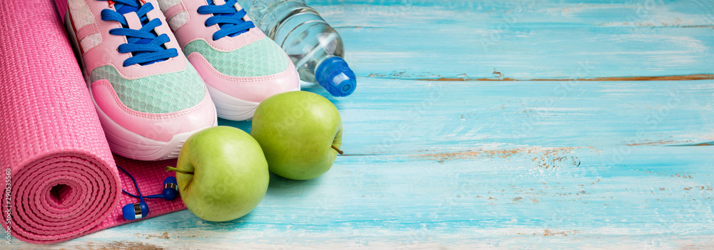 Pink yoga mat, sport shoes, bottle of water and apples on blue wooden background. Sport, healthy lifestyle, yoga concept. Female sport equipment. Copy space - obrazy, fototapety, plakaty 