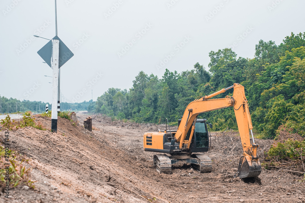 Excavator backhoe working on area adjustment beside the road.