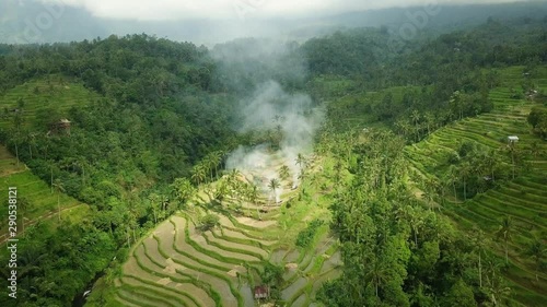 Aerial view of huge rice terrace fields in mountains with smoke from fire in countryside.