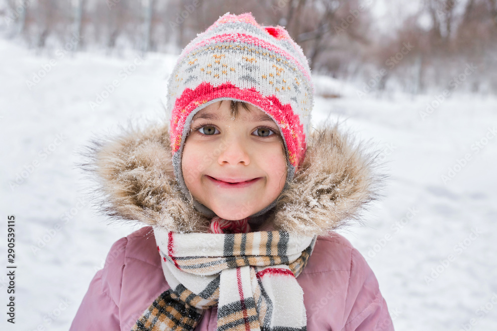 Outdoor portrait of a little girl in winter in the forest. Winter holidays, active lifestyle.
