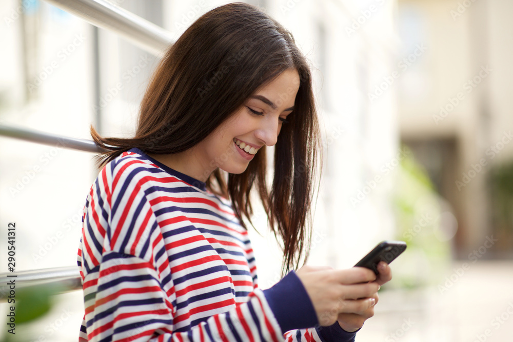 Side of happy young woman looking at cellphone Side of happy young woman looking at cellphone