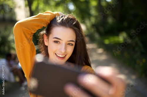 cheerful young woman taking selfie in the park