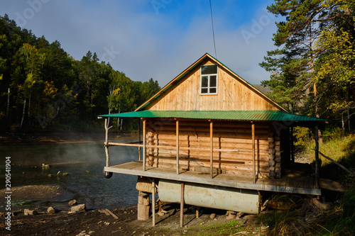 House hunting on the shore of the lake at dawn in the fog. Log home, lake mist