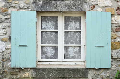 Fenêtre avec des volets vert. La façade est en pierre  © kimcass