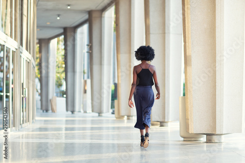 A young fashionable Afro-American woman walking away from the camera