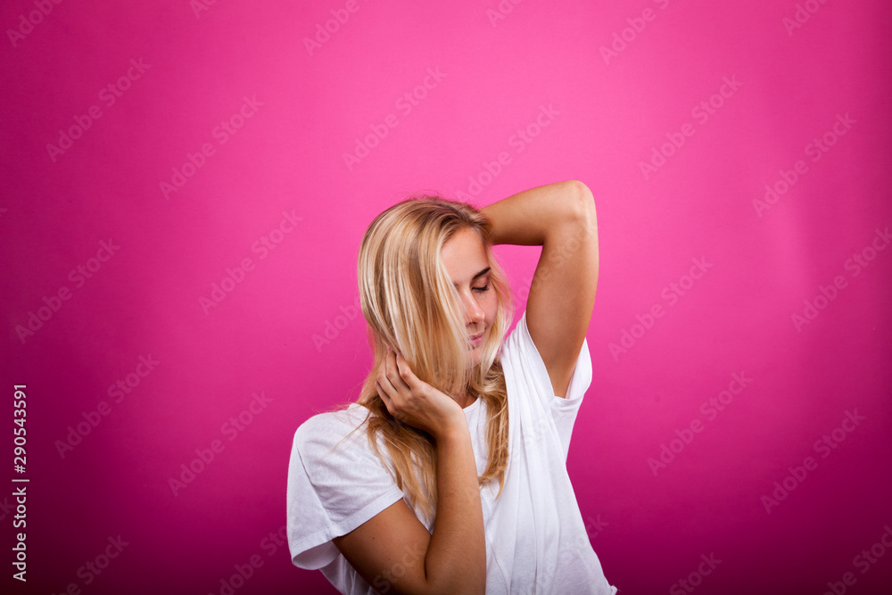 blonde in white shirt isolated against pink background blonde in white shirt isolated against pink background