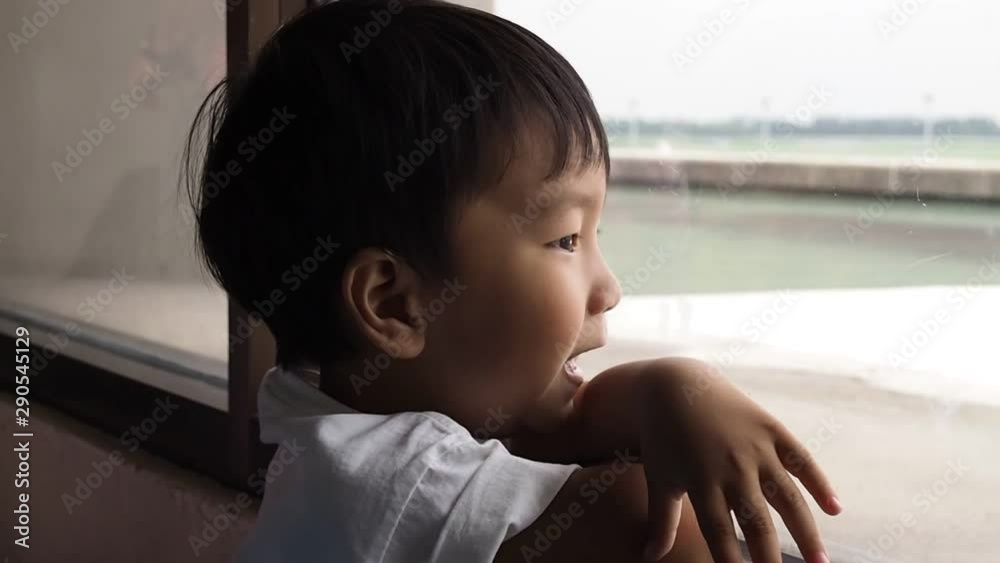 Asian child boy looking for plane through window at airport with happiness, freedom, relax time.Young kid with happy fun day in holiday. Asian child boy looking for plane through window at airport with happiness, freedom, relax time.Young kid with happy fun day in holiday.