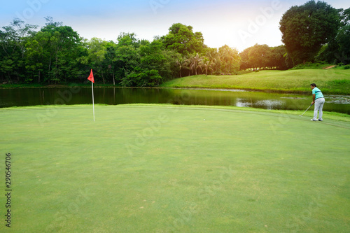 Golfer playing golf into the hole in beautiful golf course. The evening golf course with sunset in thailand