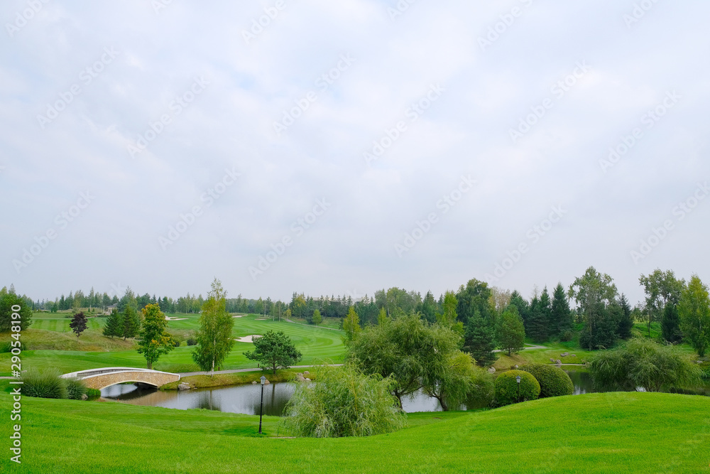 Landscape. Hills with green lawn and ornamental shrubs and trees lake and bridge. Beautiful garden Landscape. Hills with green lawn and ornamental shrubs and trees lake and bridge. Beautiful garden