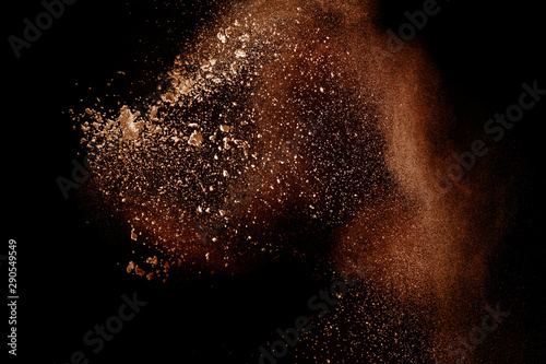Freeze motion of brown dust explosion.Stopping the movement of brown powder. Explosive brown powder on black background. photo