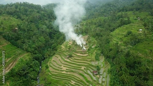 Aerial view of huge rice terrace fields in mountains with smoke from fire in countryside.