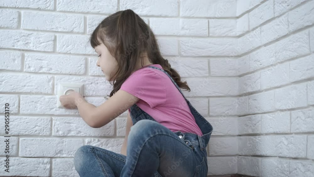 Protection against children in the socket. The little girl is unable to pull the childproof protection out of the socket. Protection against children in the socket. The little girl is unable to pull the childproof protection out of the socket.