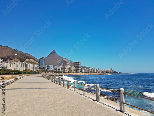 Fototapeta Mountains, hotels and deep blue water with waves at the Sea Point, beach promenade in Cape Town South Africa