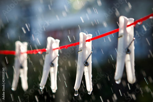 White clothes pegs on a red washing line in the rain photo