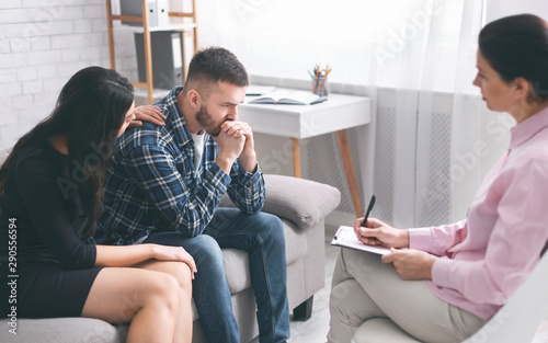 Caring wife comforting her stressed husband at psychological session photo