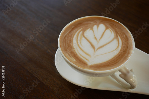 cappuccino coffee cup with beautiful latte art on old dark wooden table in coffee shop.