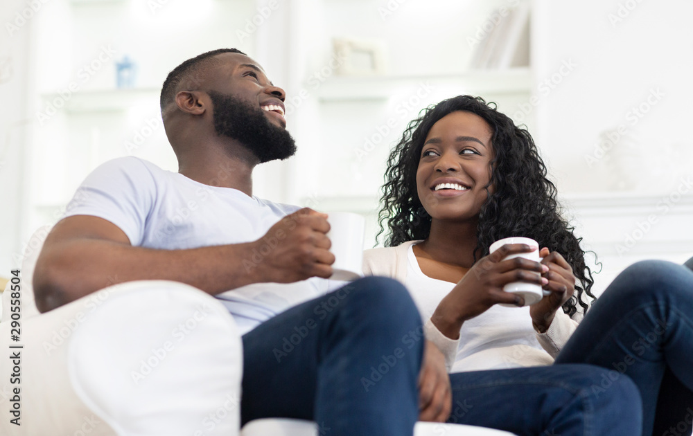 Cheerful black couple relaxing with cup of coffee at home Cheerful black couple relaxing with cup of coffee at home