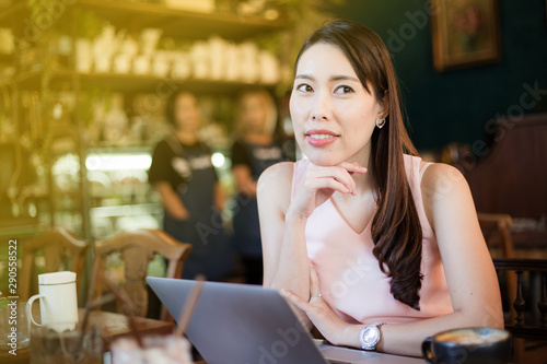 Asian business women sitting in art cafe use laptop computer