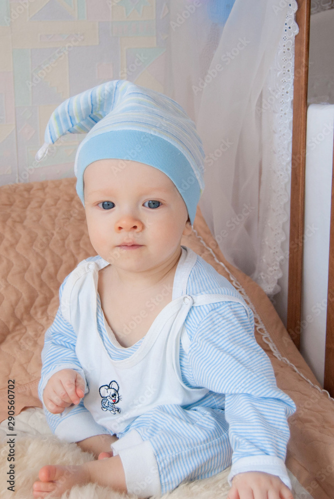 Funny cute baby boy in a gnome hat in a bed