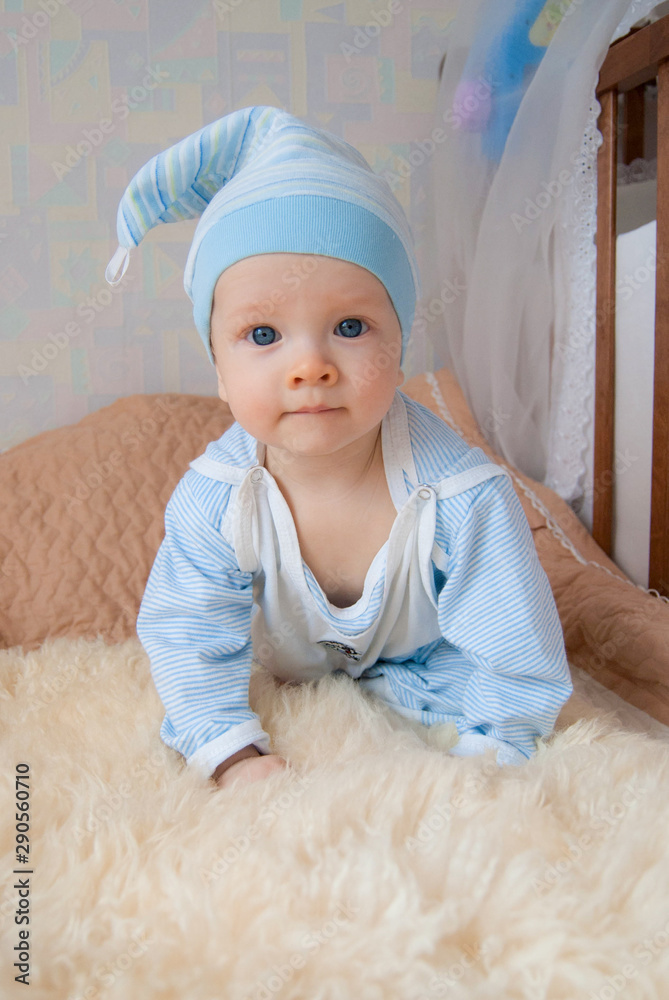 Funny cute baby boy in a gnome hat in a bed