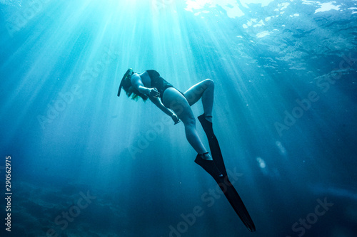 A lady in the water arching backwards with fins and snorkeling mask. photo