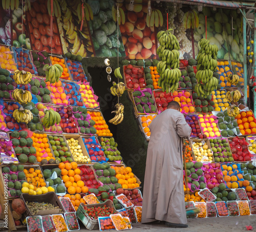 A man sweeps the sidewalk by an enormous display of colorful fruit. photo