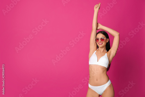 Beautiful young woman in white bikini with sunglasses on pink background. Space for text