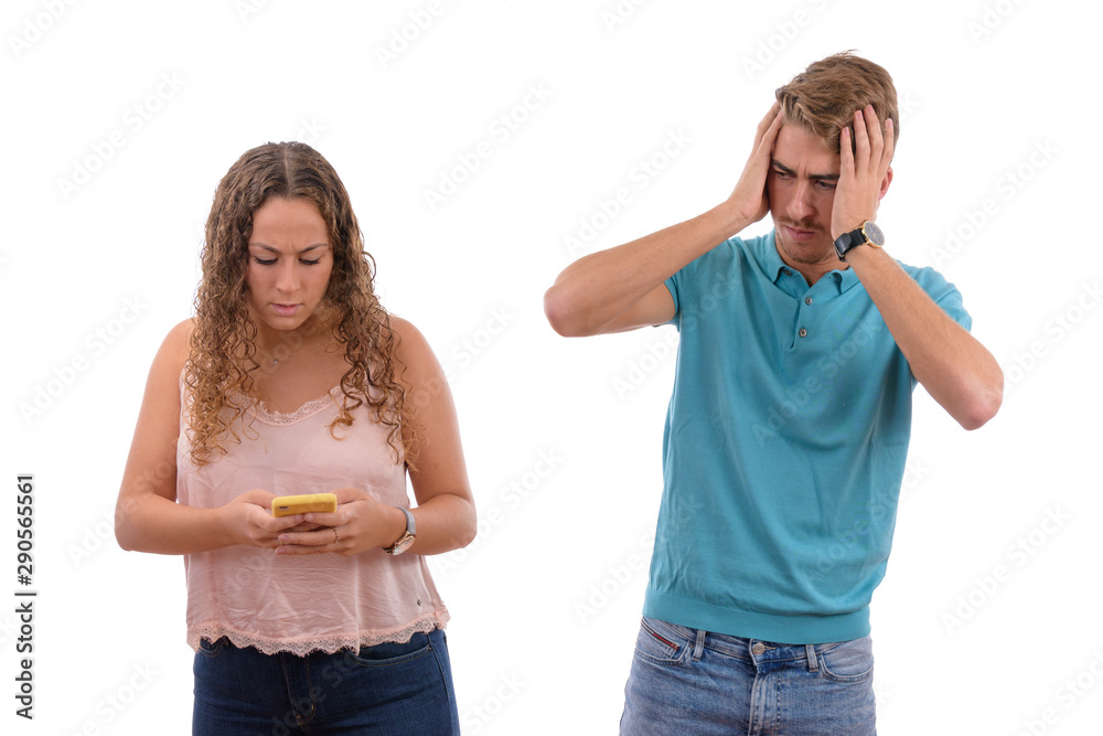 Young Caucasian couple or brothers receiving bad news on their mobile phone looking worried or shocked in white background isolated, boy dressed in blue shirt and pink girl Young Caucasian couple or brothers receiving bad news on their mobile phone looking worried or shocked in white background isolated, boy dressed in blue shirt and pink girl