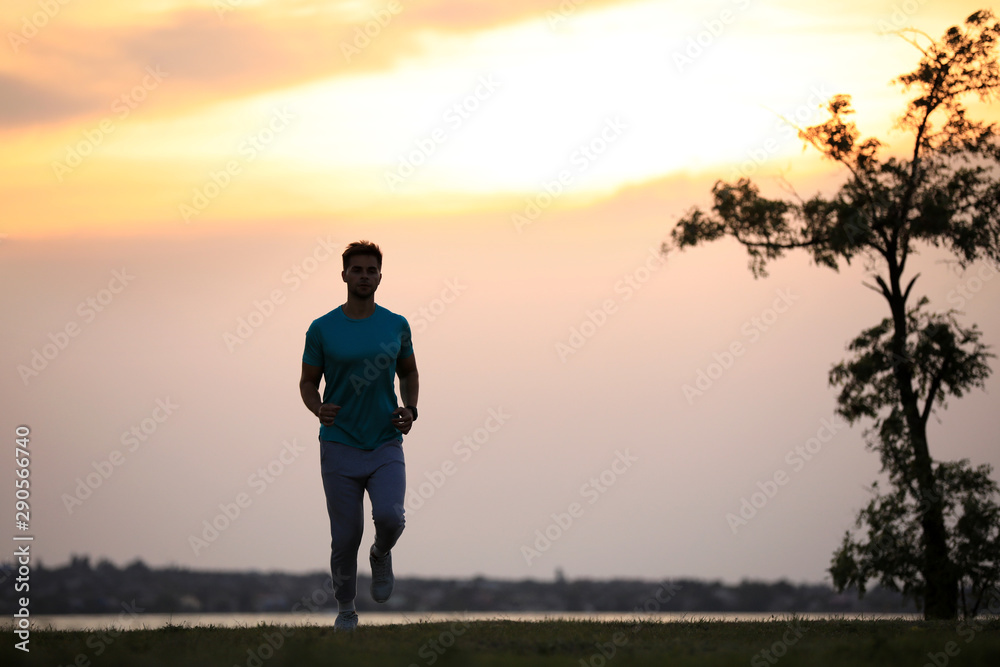Young man running outdoors in evening. Space for text - obrazy, fototapety, plakaty 