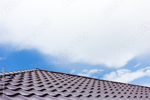 Red roof of house  on background of blue sky with clouds.