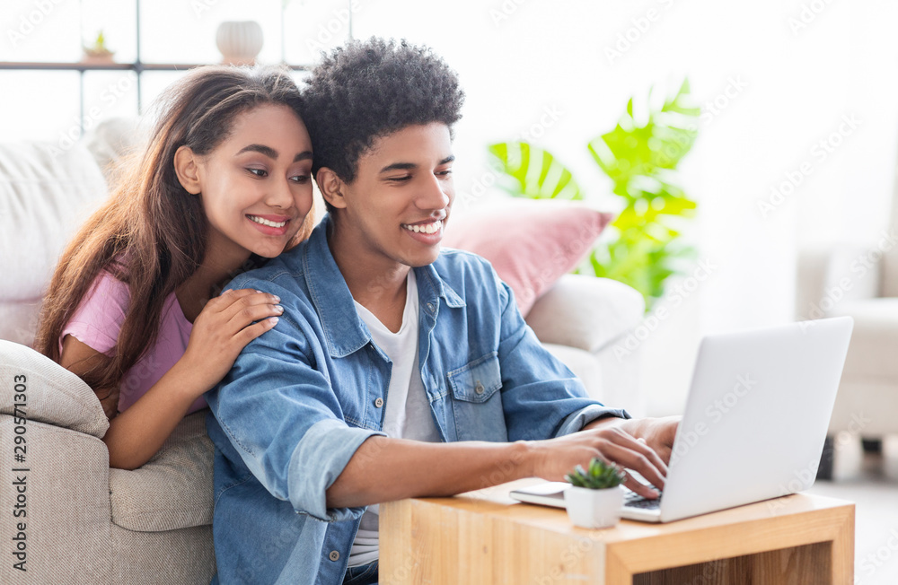 Happy african teen couple working together on laptop at home. Happy african teen couple working together on laptop at home.