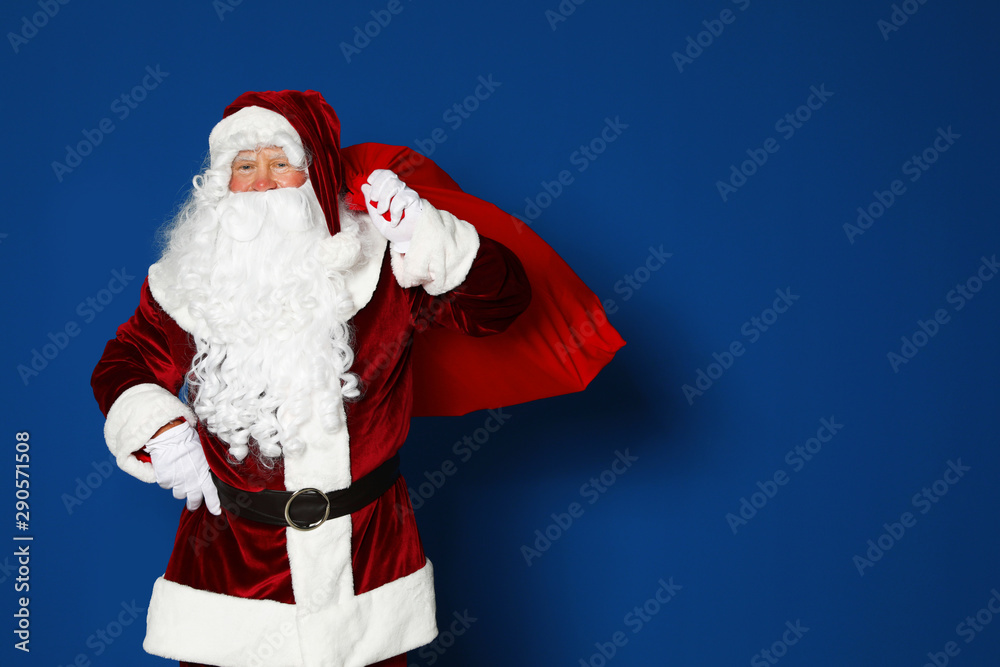Happy authentic Santa Claus with bag full of gifts on blue background. Space for text Happy authentic Santa Claus with bag full of gifts on blue background. Space for text