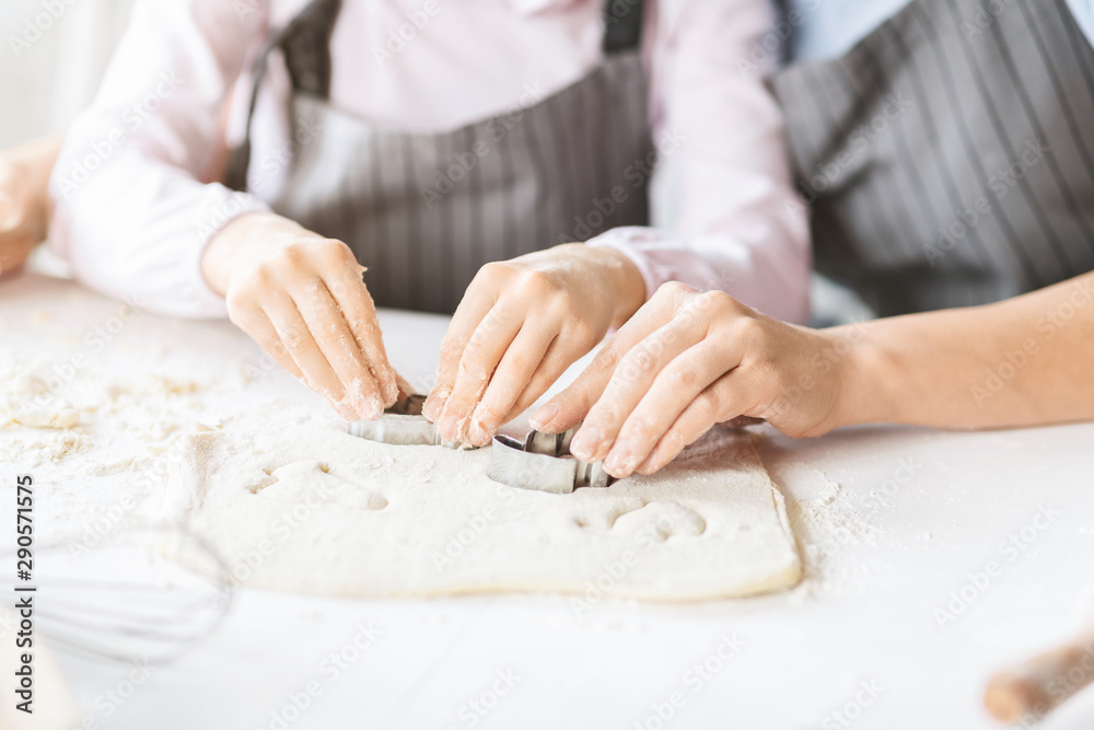 Mother and daughter cutting out different cookie shapes of dough Mother and daughter cutting out different cookie shapes of dough