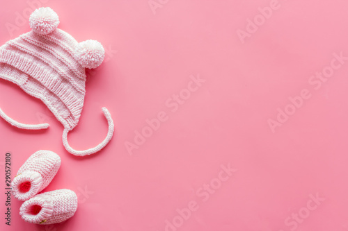 Booties and hat for newborn girl on pink background top view mockup